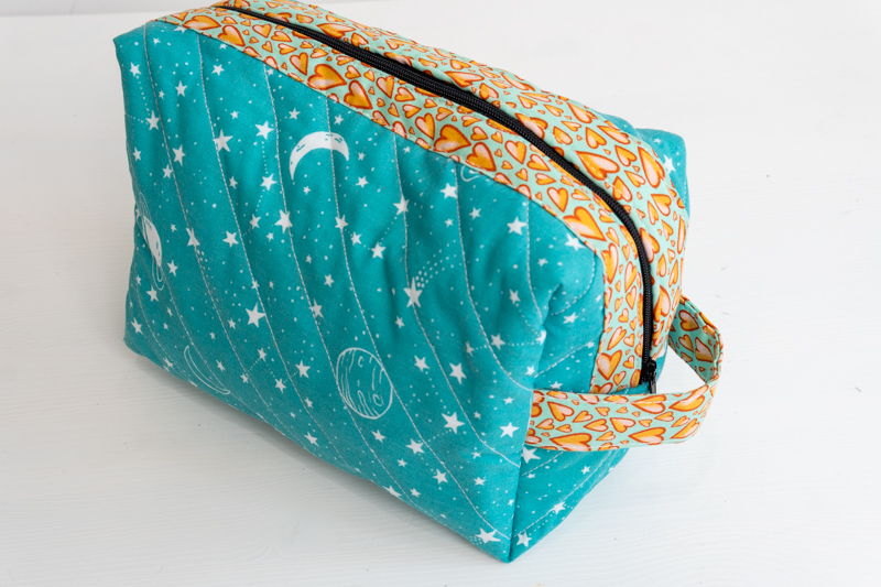 A quilted zipper pouch with handle made in space print polycotton and cotton trim